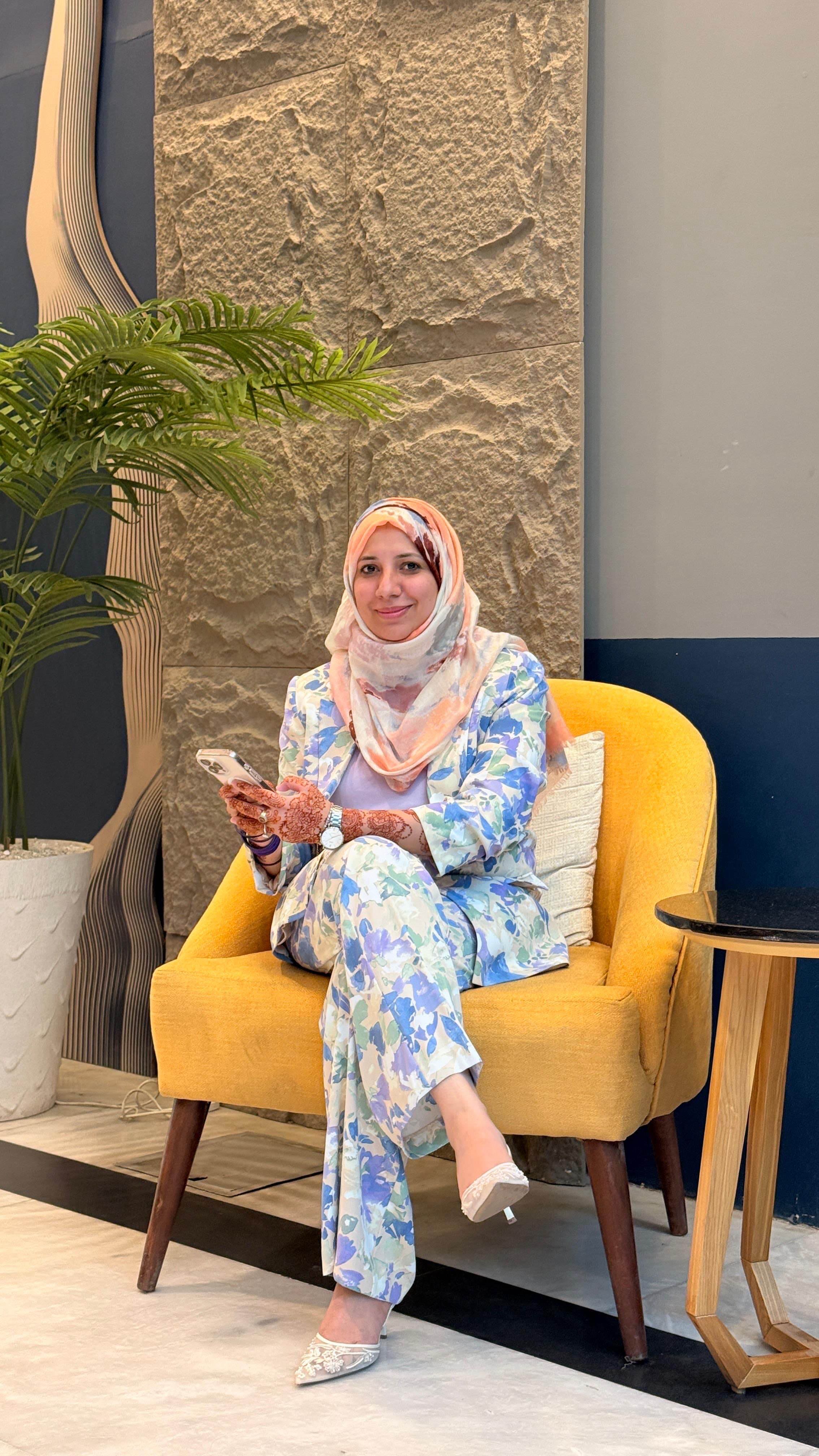 Rabia Sabir seated, working from a phone